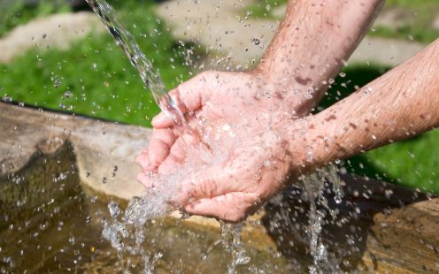 two hands under sparkling fresh drinking water of a well